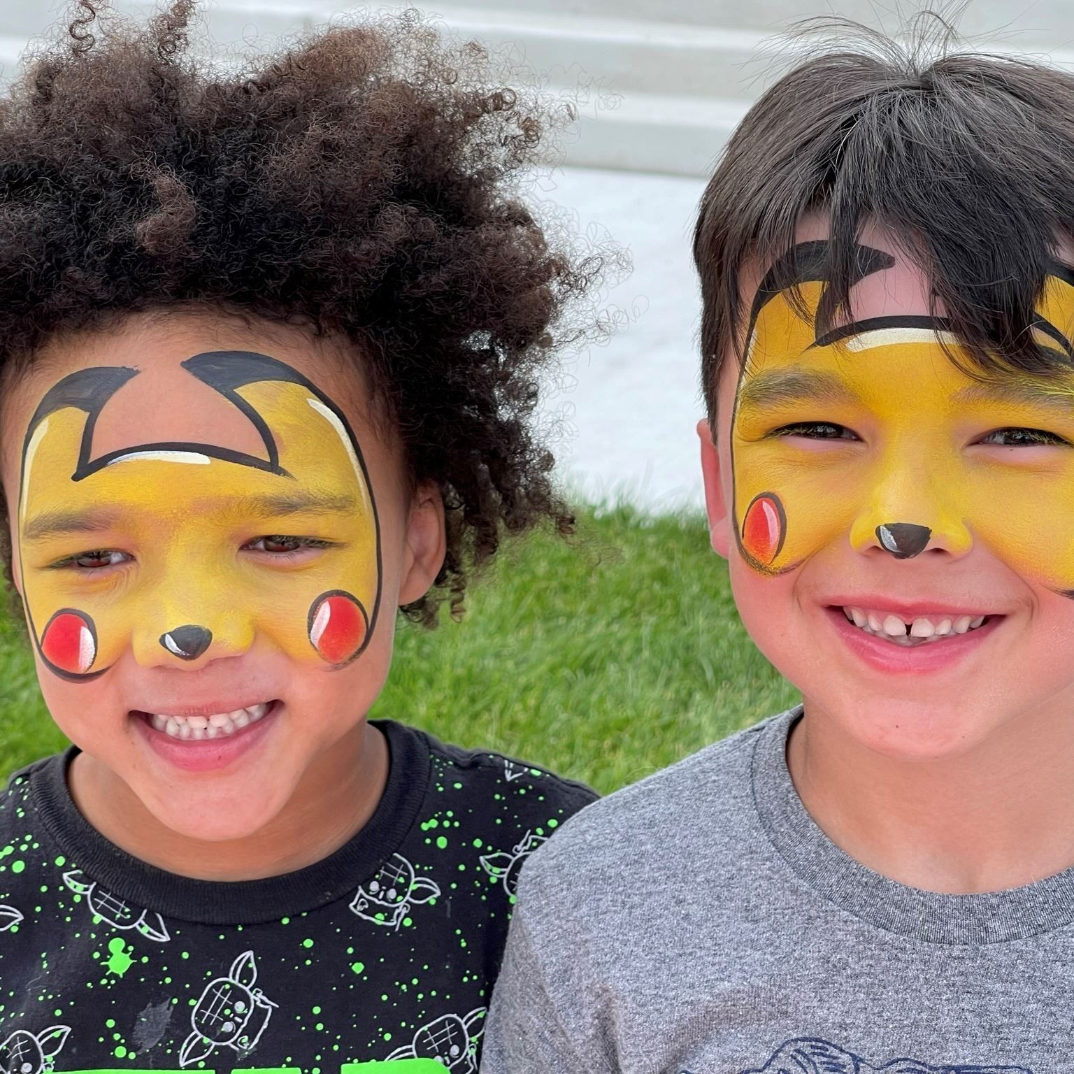 Two chillren with their faces painted to look like Pikachu.