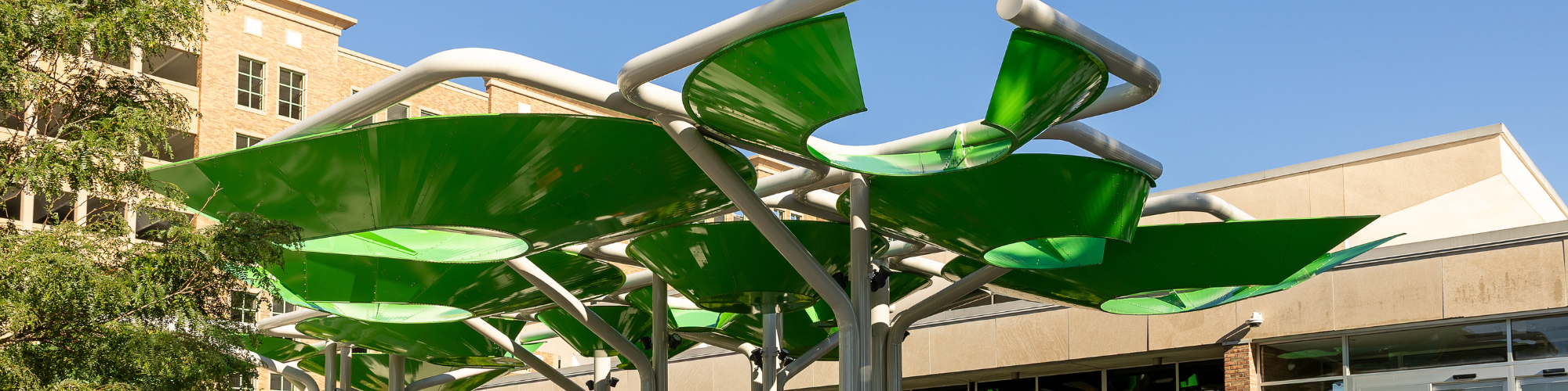 Art installation with green, leaf-shaped panels forming a canopy at the entrance of the Library.